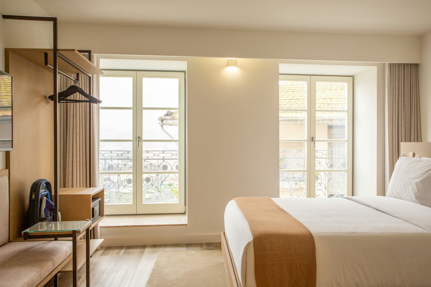 Camera d'albergo con letto rifatto e vista sulla città.