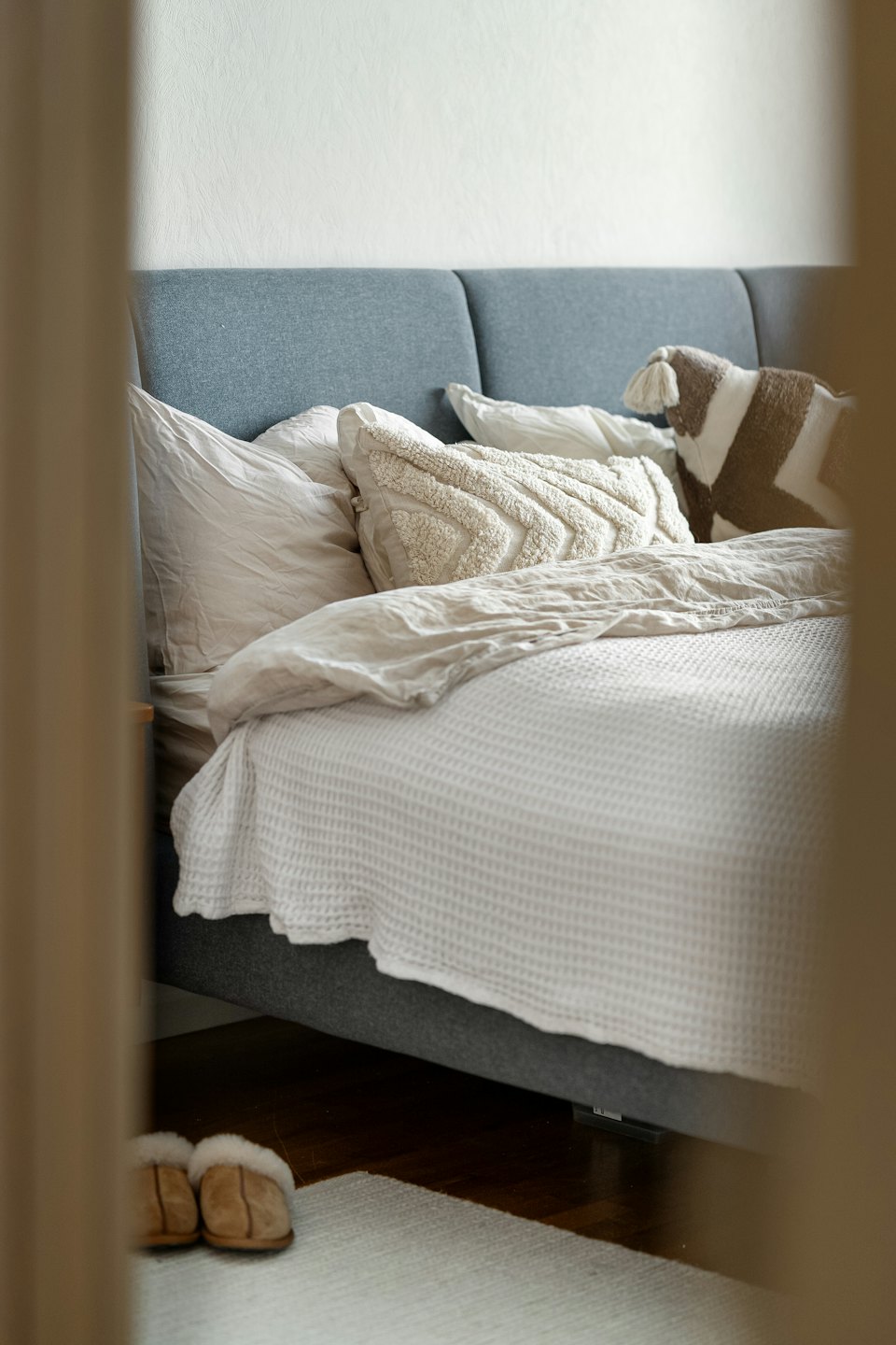 Camera da letto accogliente con letto rifatto e pantofole morbide sul tappeto.