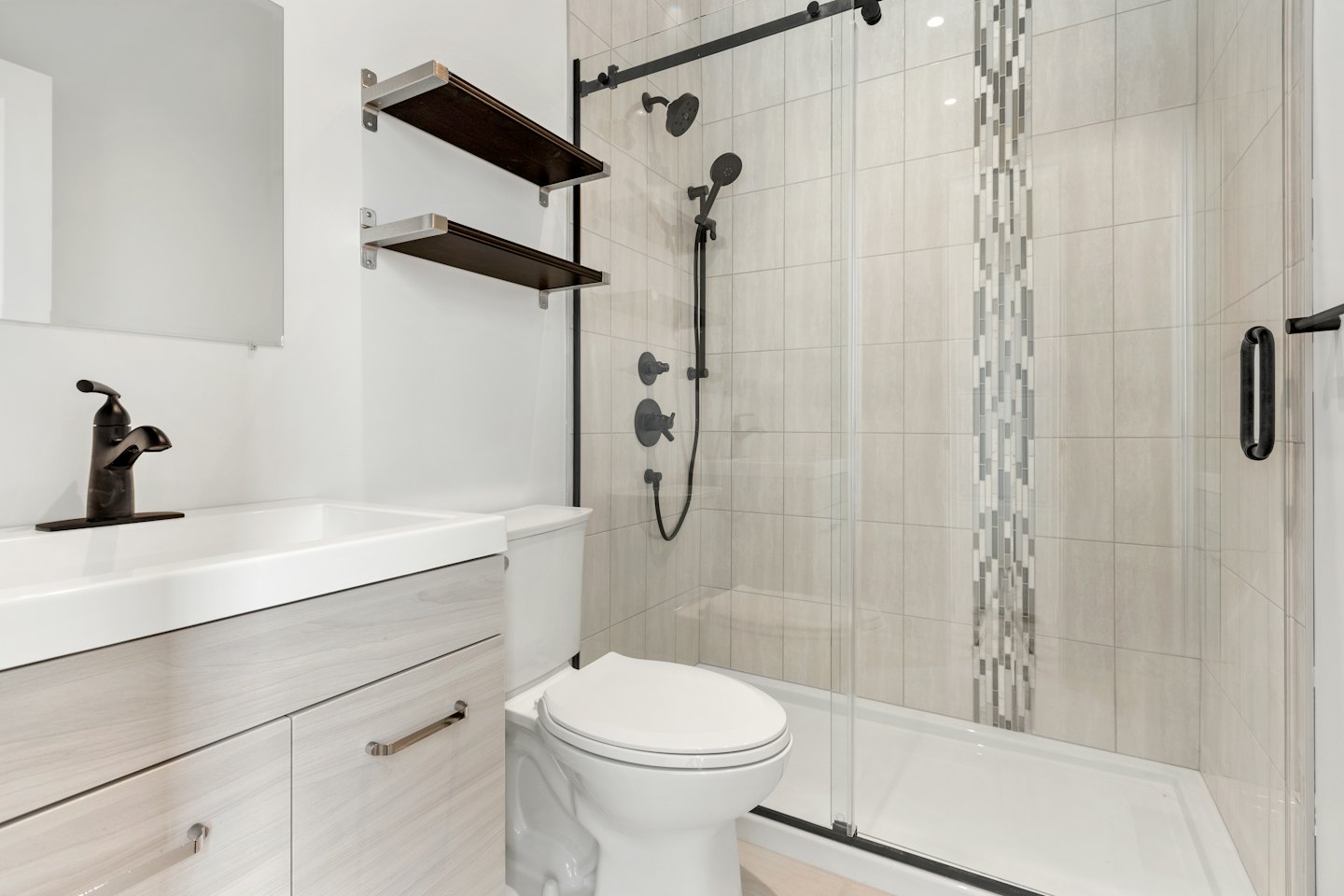 Bagno moderno con rubinetteria nero opaco e mobiletto in legno chiaro.
